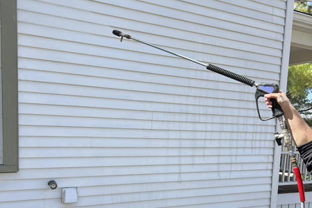 Technician performing soft washing on vinyl siding in prairie du sac wi